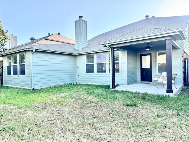 rear view of house with a lawn, a chimney, and a patio area