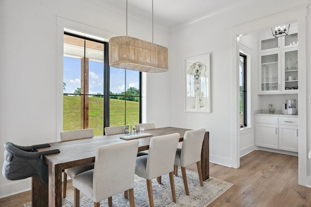 dining area with crown molding, a notable chandelier, a wealth of natural light, and light wood finished floors