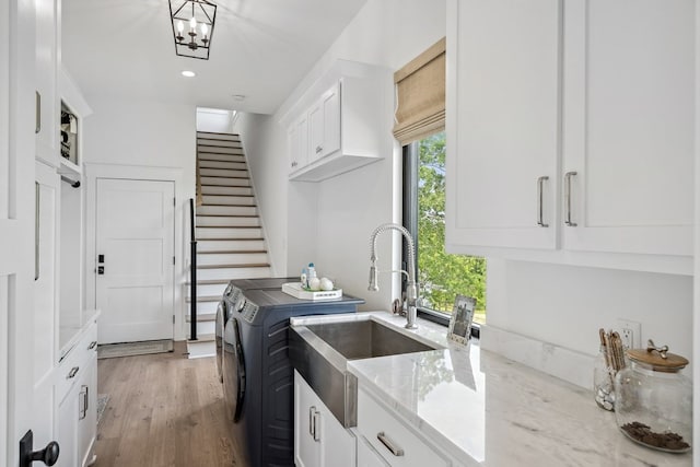 laundry area featuring independent washer and dryer, light wood-type flooring, cabinet space, a sink, and recessed lighting