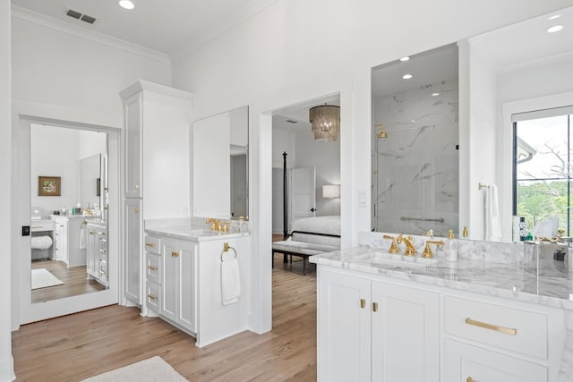 ensuite bathroom with a sink, a marble finish shower, ensuite bathroom, visible vents, and ornamental molding