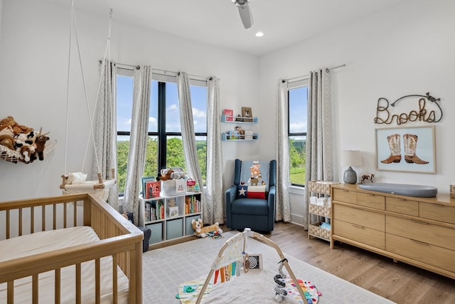 bedroom with recessed lighting, a ceiling fan, a crib, and light wood finished floors