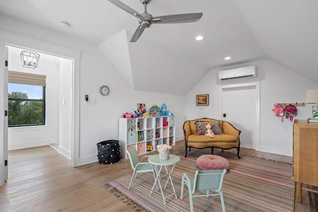 sitting room featuring wood finished floors, lofted ceiling, baseboards, a wall unit AC, and a ceiling fan
