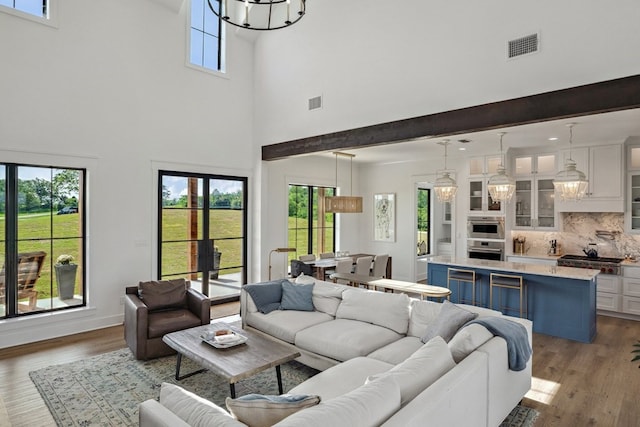 living room with baseboards, a high ceiling, wood finished floors, and visible vents