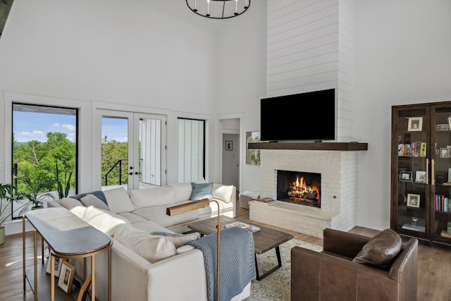 living room with wood finished floors, a high ceiling, a fireplace, and french doors