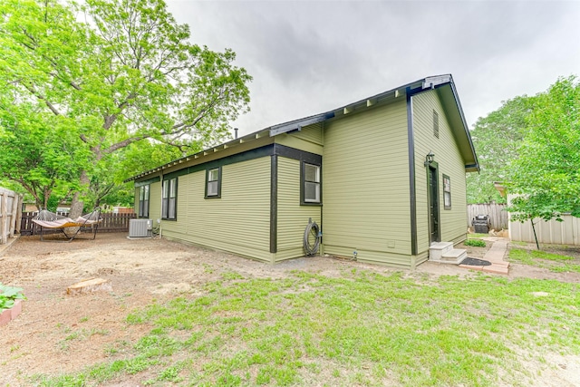 rear view of house featuring a yard, fence, cooling unit, and entry steps