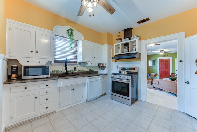kitchen with stainless steel appliances, a ceiling fan, dark countertops, and a sink
