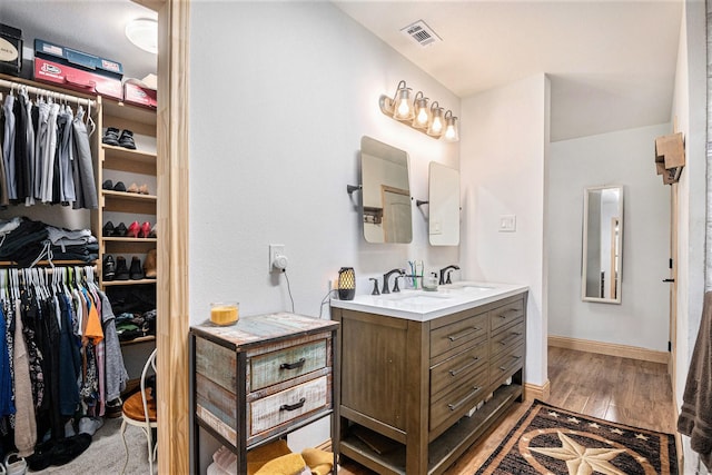 full bath with a walk in closet, visible vents, wood finished floors, and vanity