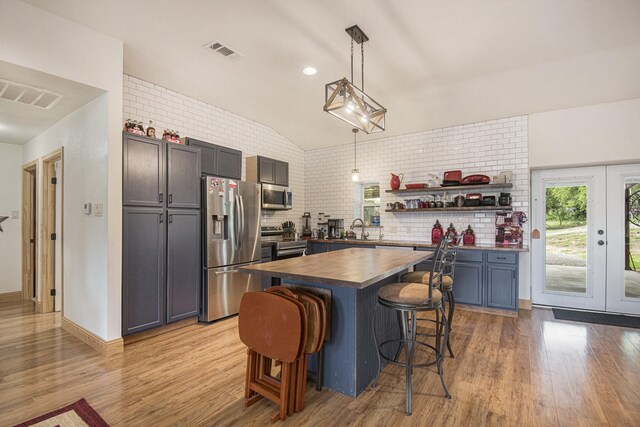 kitchen featuring visible vents, a sink, wood counters, vaulted ceiling, and stainless steel appliances