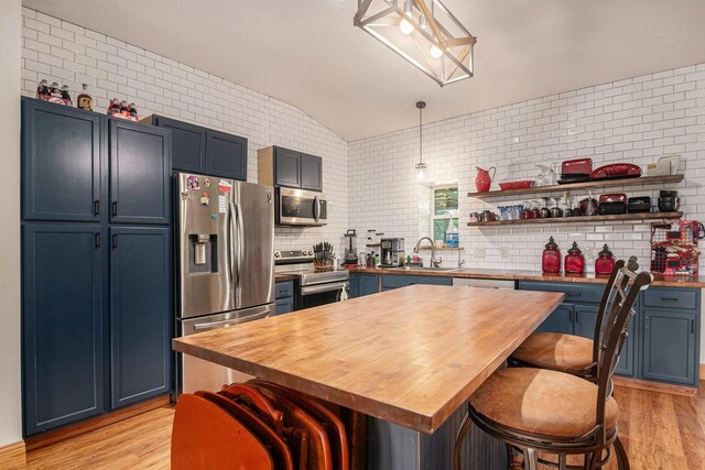 kitchen with light wood-style flooring, appliances with stainless steel finishes, wooden counters, and a breakfast bar
