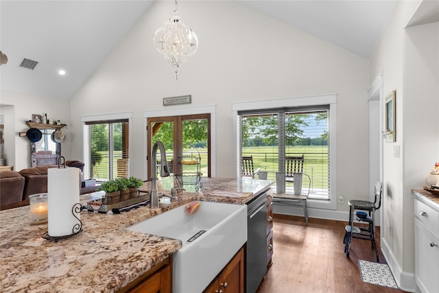 kitchen featuring visible vents, stainless steel dishwasher, a sink, high vaulted ceiling, and dark wood-style floors