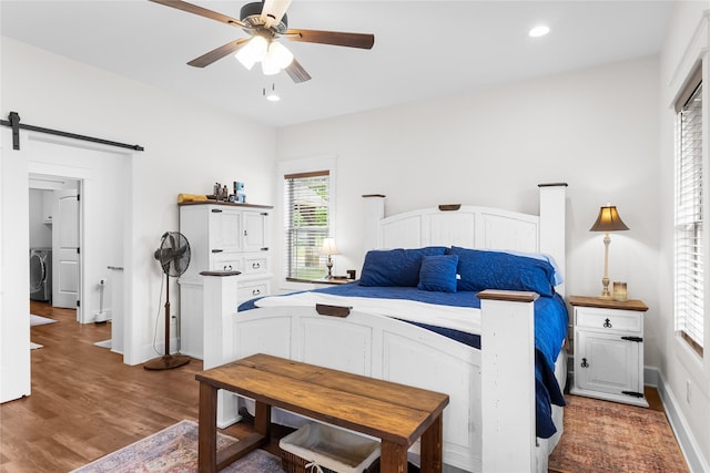 bedroom with wood finished floors, baseboards, washer / clothes dryer, recessed lighting, and a barn door