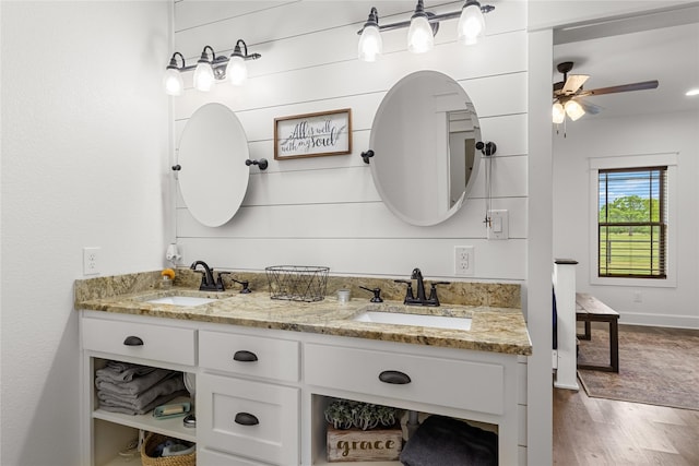 bathroom with a sink, ceiling fan, double vanity, and wood finished floors