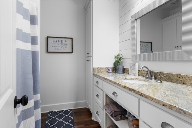 bathroom with baseboards, curtained shower, wood finished floors, and vanity