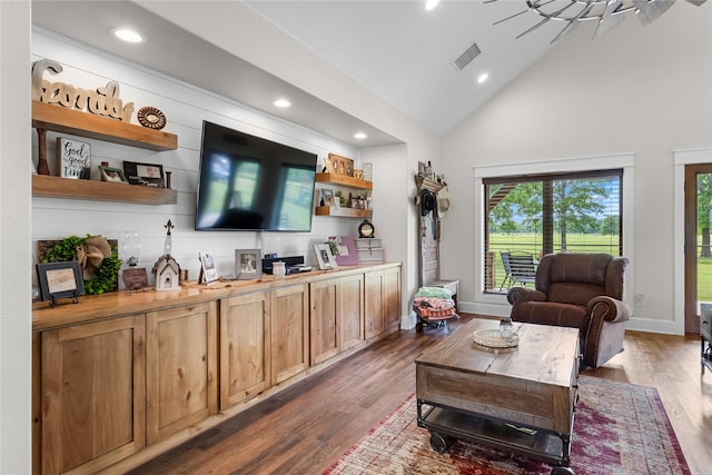 living area with visible vents, wood finished floors, baseboards, high vaulted ceiling, and recessed lighting