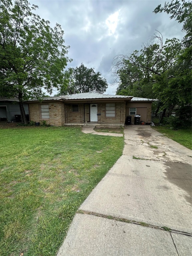 single story home featuring metal roof, concrete driveway, and a front lawn