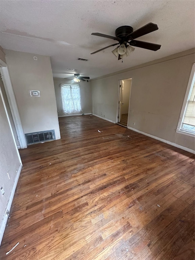 unfurnished room with baseboards, wood-type flooring, a ceiling fan, and visible vents
