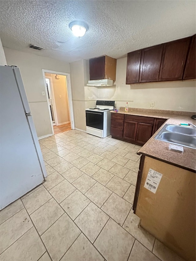 kitchen with white appliances, a textured ceiling, under cabinet range hood, a sink, and light tile patterned floors