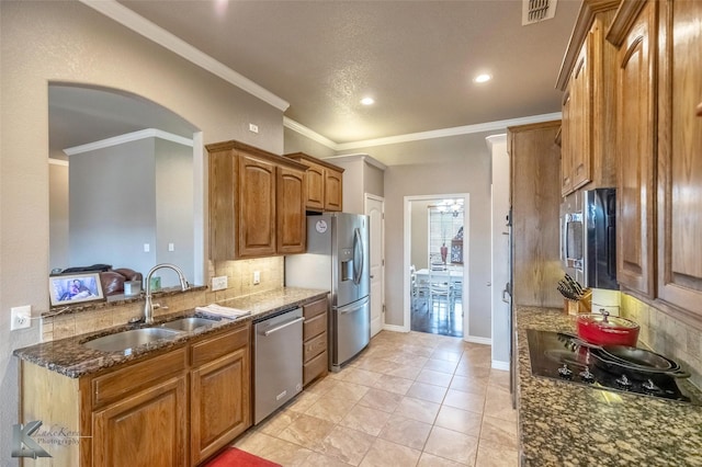 102 Wait Station Ave, Tuscola, TX 79562 - kitchen featuring appliances with stainless steel finishes, a sink, tasteful backsplash, dark stone counters, and brown cabinetry