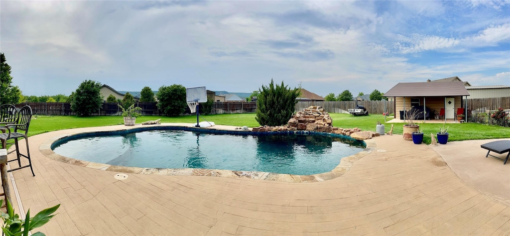 view of swimming pool with a yard, a fenced in pool, and a fenced backyard