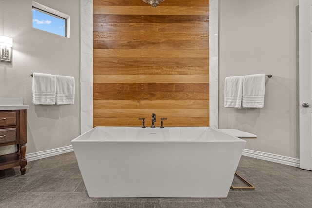 bathroom with a freestanding tub, baseboards, and vanity