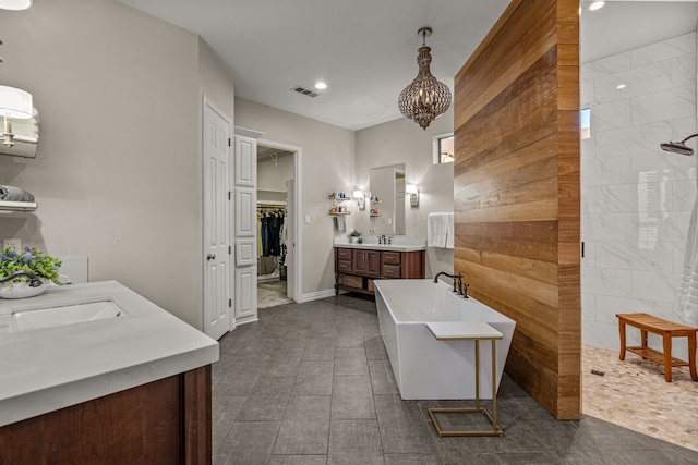 full bathroom with visible vents, recessed lighting, two vanities, a soaking tub, and a sink