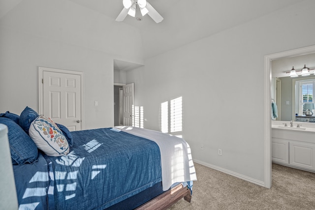 bedroom featuring ceiling fan, light colored carpet, a sink, baseboards, and ensuite bathroom