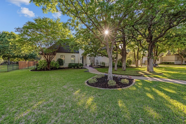 view of front of house with a front lawn, stucco siding, and fence