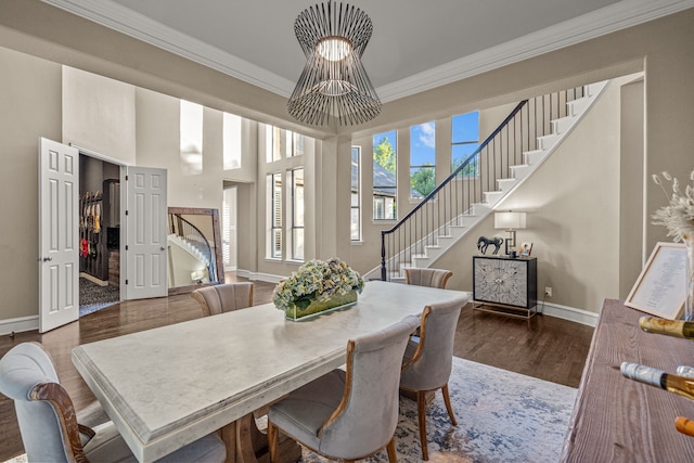 dining space featuring crown molding, baseboards, wood finished floors, and stairway