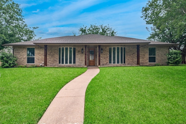 ranch-style house featuring brick siding, a shingled roof, and a front lawn