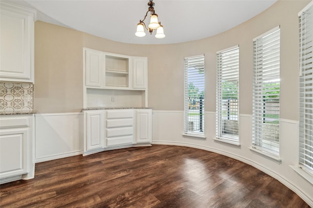unfurnished dining area with dark wood-type flooring and a chandelier