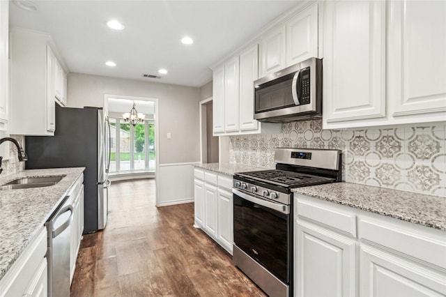 kitchen with appliances with stainless steel finishes, a sink, dark wood-style floors, a chandelier, and white cabinetry