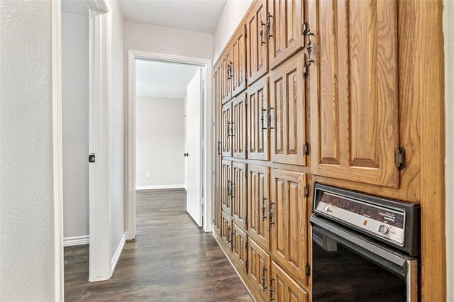 hallway featuring baseboards and dark wood finished floors