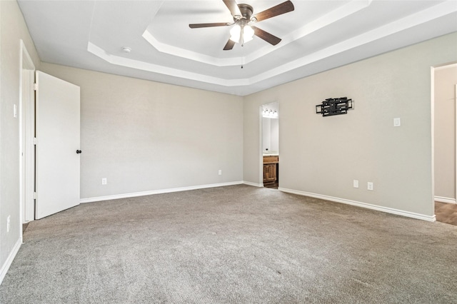 empty room featuring baseboards, ceiling fan, carpet, and a tray ceiling