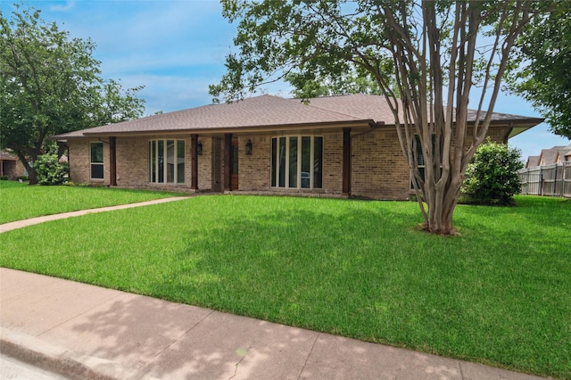 single story home featuring brick siding, fence, and a front lawn