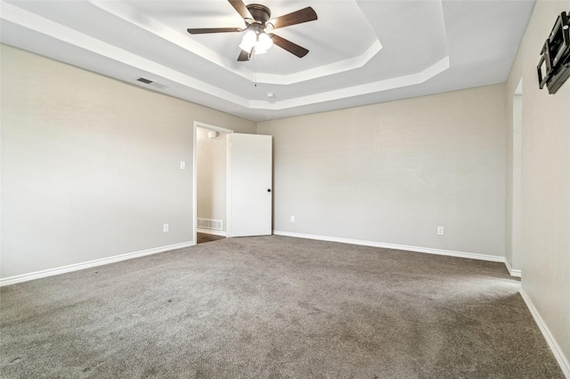 carpeted empty room featuring visible vents, a ceiling fan, a raised ceiling, and baseboards