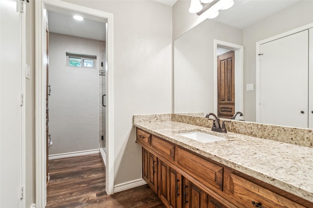 full bath featuring baseboards, a shower stall, vanity, and wood finished floors