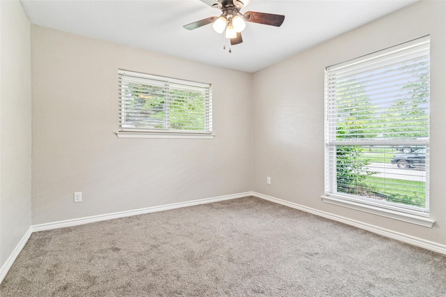 carpeted spare room featuring a ceiling fan and baseboards