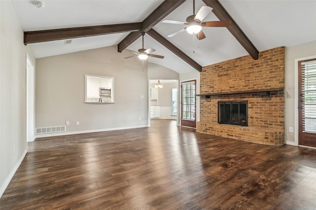 unfurnished living room with wood finished floors, ceiling fan with notable chandelier, a brick fireplace, and visible vents