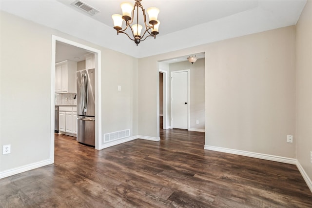 empty room with dark wood-style flooring, a chandelier, baseboards, and visible vents