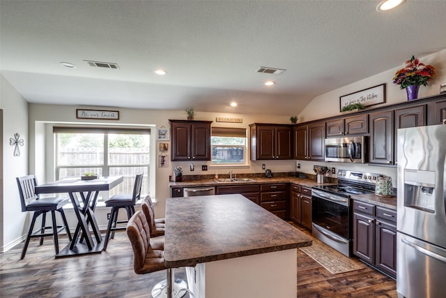 kitchen featuring dark brown cabinetry, visible vents, dark countertops, a sink, and stainless steel appliances