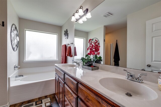full bath with visible vents, a sink, a bath, and wood finished floors