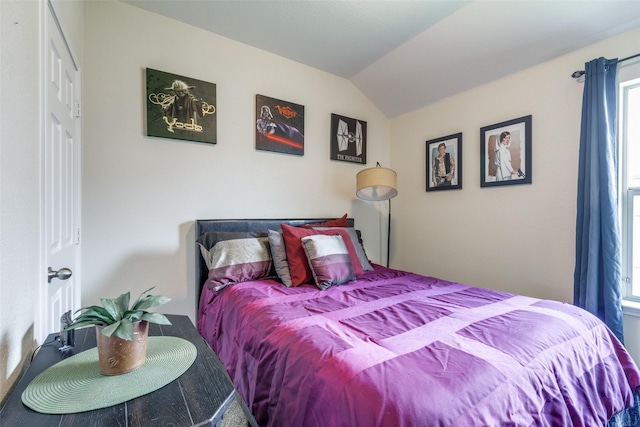 bedroom with carpet floors, vaulted ceiling, and multiple windows