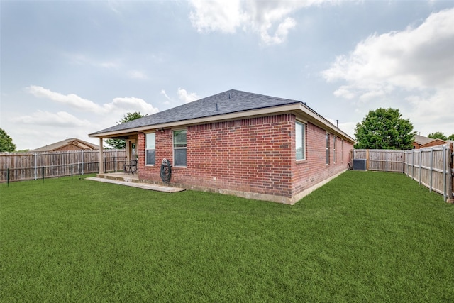 rear view of house featuring brick siding, a fenced backyard, and a yard