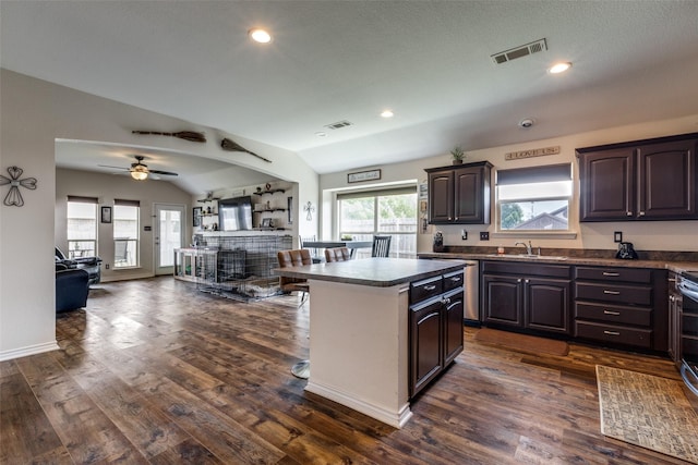 kitchen featuring visible vents, dark countertops, dark brown cabinets, a sink, and open floor plan
