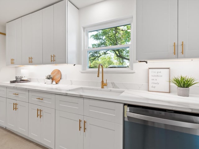 kitchen featuring light tile patterned flooring, light stone countertops, white cabinets, a sink, and dishwasher