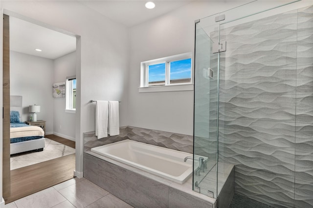 ensuite bathroom featuring connected bathroom, plenty of natural light, a garden tub, and a stall shower