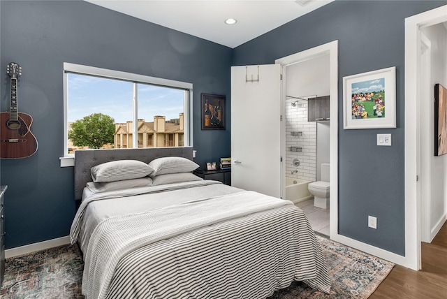 bedroom featuring baseboards, ensuite bath, and wood finished floors