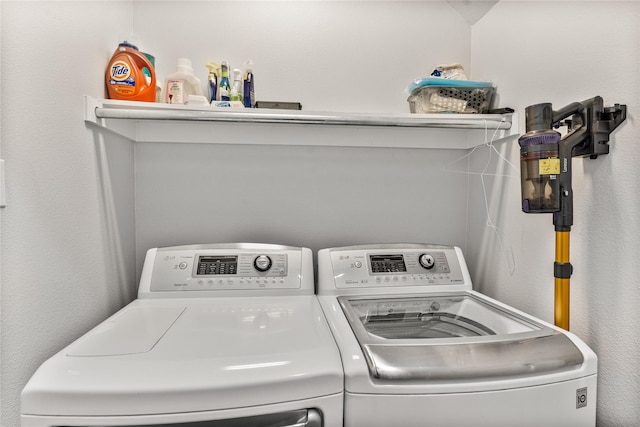 clothes washing area with a textured wall, laundry area, and independent washer and dryer