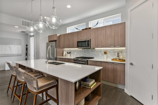 kitchen featuring visible vents, brown cabinetry, modern cabinets, a sink, and premium appliances