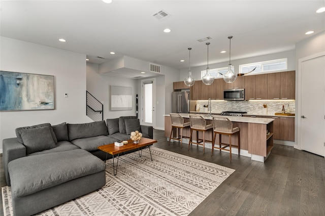 living area with dark wood-style flooring, visible vents, and recessed lighting